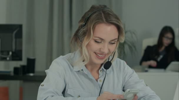 Sorrindo mulher de escritório mensagens de texto no telefone em seu local de trabalho — Vídeo de Stock