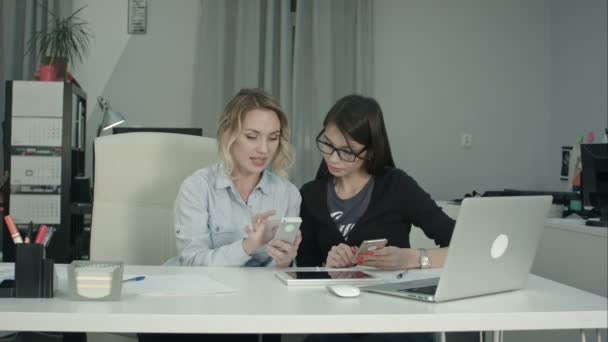 Старший менеджер показывает молодому интерну в очках, как пользоваться мобильным приложением — стоковое видео