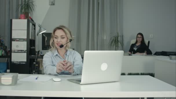 Две улыбающиеся женщины, работающие в колл-центре, отвечают на звонки — стоковое видео