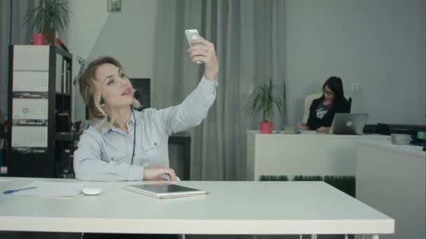 Vacker ung kontorist i headsetet tar selfies med telefon — Stockvideo