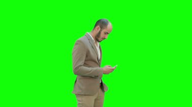 İş adamı bir yeşil ekran, Chroma Key telefonda mesaj içinde yürür.