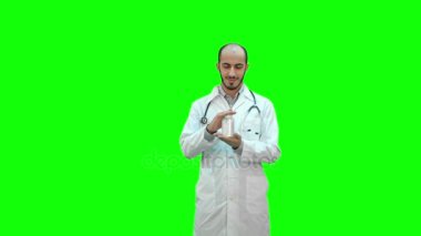 Hap tavsiye ve Chroma Key bir yeşil ekranda bir başparmak gösterilmesini doktor gülümseyen.