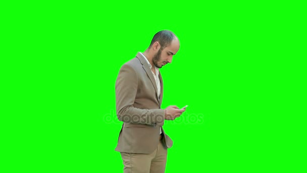 Hombre de negocios camina en mensajes de texto en el teléfono en una pantalla verde, Clave de croma . — Vídeos de Stock