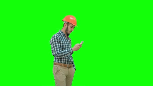 Mladý manažer v helmě pomocí mobilního telefonu na zelené obrazovce, Chroma Key. — Stock video