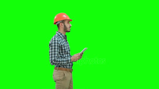 Ingeniero del contratista en hardhat que inspecciona el sitio de construcción que sostiene la tableta digital en una pantalla verde, llave del croma . — Vídeo de stock