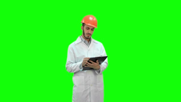 Engineer in white coat preparing report on a Green Screen, Chroma Key. — Stock Video