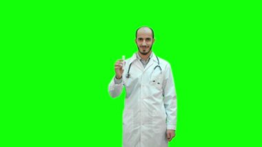 Tek tip ilaç şişesi işaret ve kameraya bir yeşil ekranda Chroma Key arıyor gülümseyen doktor.