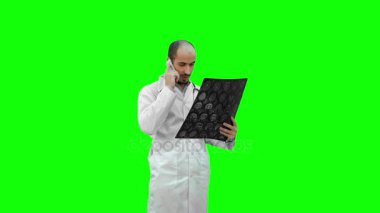 Xray sonuçları tutarak ve hastaya bir yeşil ekran, Chroma Key telefonda konuşurken doktor.