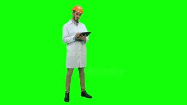 İnşaat mühendisi beyaz ceket Chroma anahtar yeşil ekranda raporu hazırlanıyor.