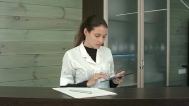 Müşteri karşılamak için onun tablet bir kenara koyarak spa resepsiyonist gülümseyen