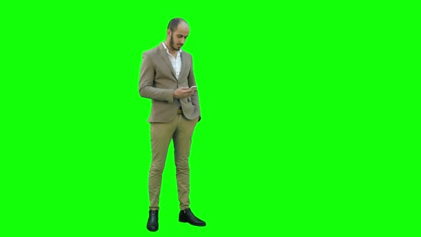 Jonge man in pak verzenden van SMS-berichten op zijn telefoon op een groen scherm, Chromakey. — Stockvideo