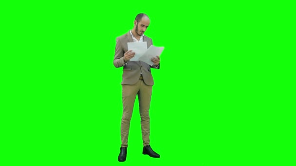 Allvarliga unga manager stående och läsning av dokument på en grön skärm, Chroma Key. — Stockvideo