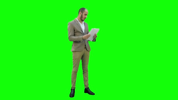 Junger Geschäftsmann studiert aufmerksam Dokumente auf einem grünen Bildschirm, Chroma-Schlüssel. — Stockvideo