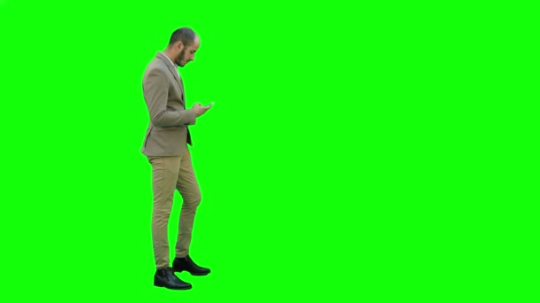 Hombre de negocios entra comprobando su teléfono en una pantalla verde, Chroma Key . — Vídeos de Stock