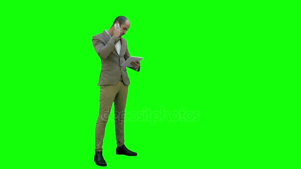 Drukke man praten aan de telefoon en tablet te houden op een groen scherm, Chromakey. — Stockvideo