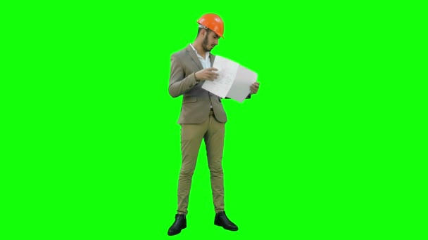 Jonge architect in helm controleren bouwplannen op een groen scherm, Chromakey. — Stockvideo
