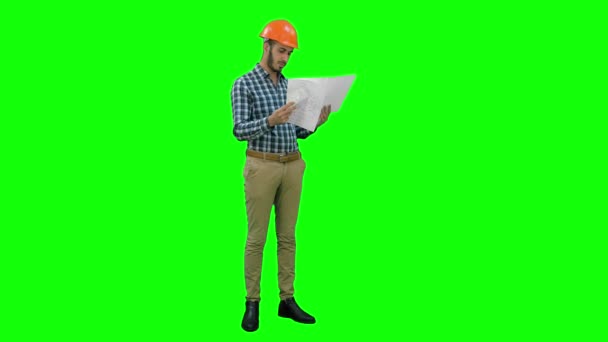 Ingeniero joven en casco comprobando dibujos de construcción en una pantalla verde, Chroma Key . — Vídeos de Stock