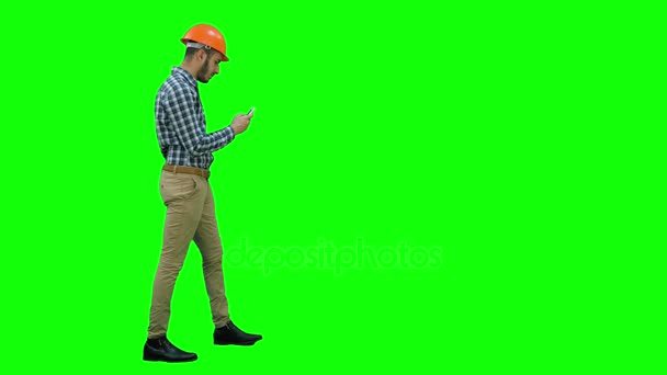 Burgerlijk ingenieur in de helm met behulp van mobiele telefoon op een groen scherm, Chromakey. — Stockvideo