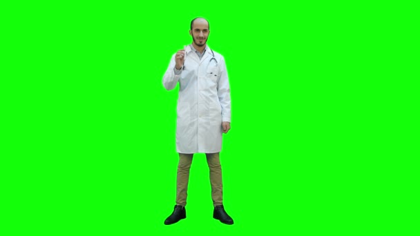 Smiling doctor in white coat pointing at medicine bottle and looking at camera on a Green Screen, Chroma Key. — Stock Video