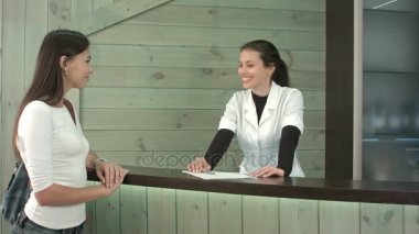 Bir kadın müşteri karşılama masasında tebrik bir spa resepsiyonist