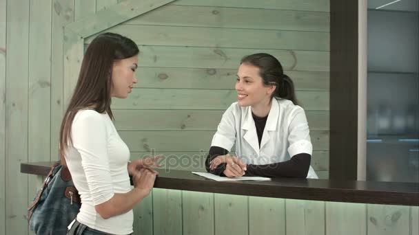 Lächelnde Wellness-Empfangsdame begrüßt eine Kundin und erzählt ihr von Dienstleistungen — Stockvideo
