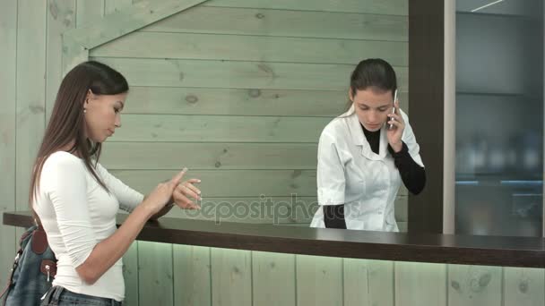 Ongeduldig vrouwelijke klant te wachten om te worden bediend door spa receptioniste praten aan de telefoon — Stockvideo