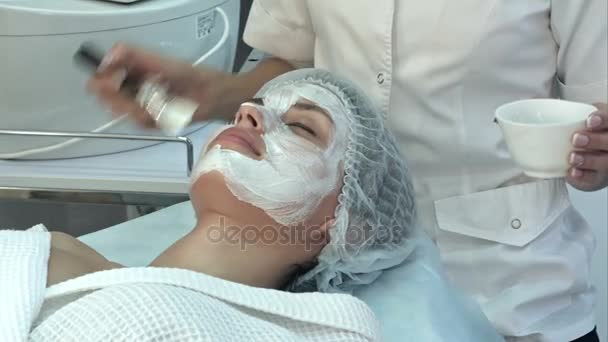 Joven hermosa chica recibiendo máscara facial de arcilla en el salón de belleza del spa — Vídeo de stock