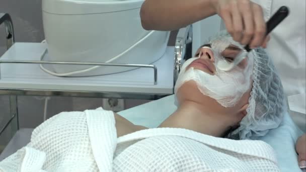 Спа-жінка наносить глиняну маску для обличчя пензлем — стокове відео