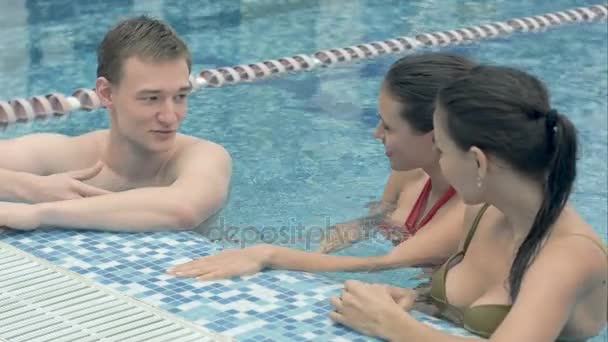 Τρεις ευτυχισμένος φίλους μιλάμε και χαλαρώνοντας στην άκρη του εσωτερική πισίνα — Αρχείο Βίντεο
