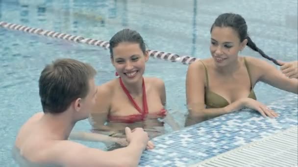 Dos hermosas mujeres hablando con un joven en la piscina — Vídeos de Stock