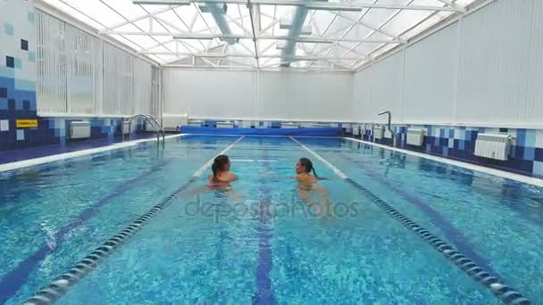 Dvě mladé ženy mluví a plavání v bazénu — Stock video