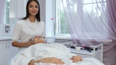 Mutlu makyajcısı genç bir kadın üzerinde yüz masajı yapıyor