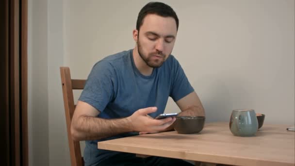 Молодой человек разговаривает по телефону посреди завтрака — стоковое видео