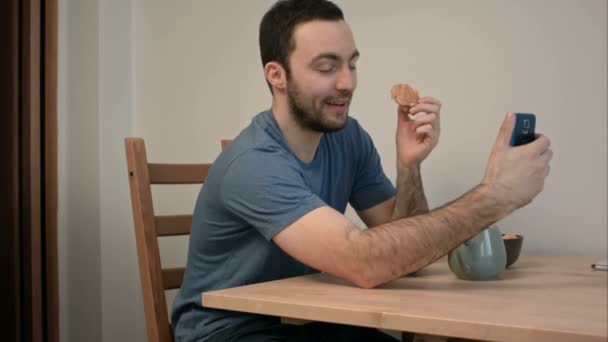 Joven tomando selfies con croissant en su teléfono durante el desayuno — Vídeos de Stock