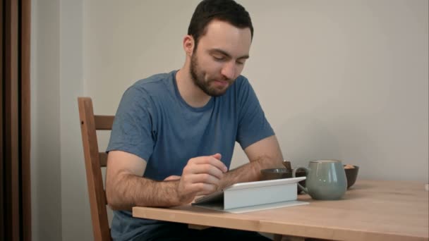 Young man having a video call via tablet over breakfast — Stock Video