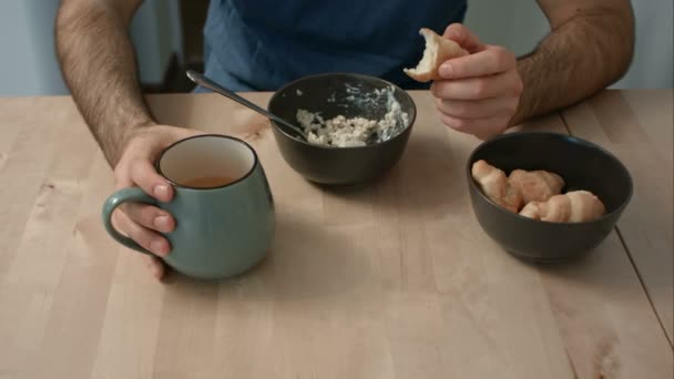 Mężczyzna jedzenie owsianka i rogaliki na śniadanie — Wideo stockowe