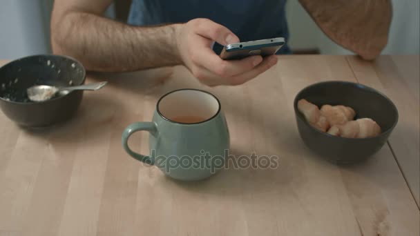 Mans handen met telefoon aan ontbijttafel — Stockvideo