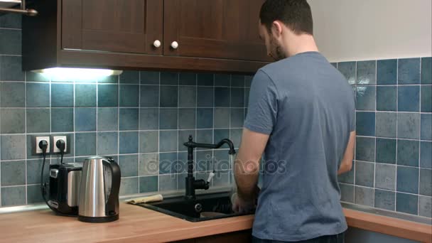 Jovem lavando pratos na cozinha — Vídeo de Stock