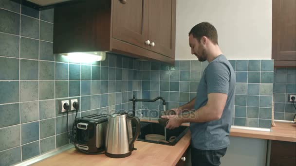 Joven lavando platos en la cocina en casa — Vídeos de Stock