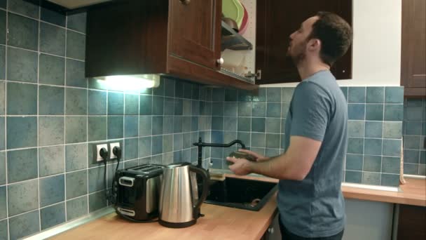 Νεαρός βάζοντας πιάτα μακριά στην κουζίνα — Αρχείο Βίντεο