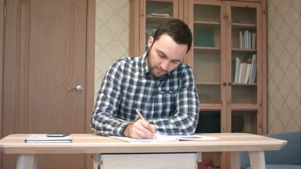 Young man taking phone call during study at home — Stock Video