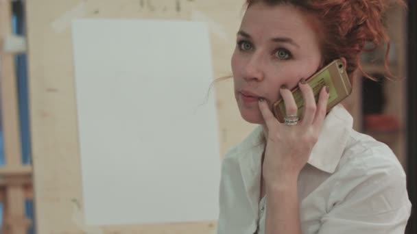 Ginger artista donna parlando al telefono accanto al cavalletto — Video Stock