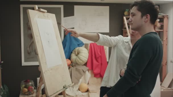 Pintora enseñando al joven a dibujar la cara clásica — Vídeo de stock