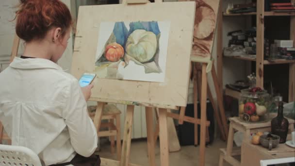 Pintora femenina usando smartphone en taller — Vídeos de Stock