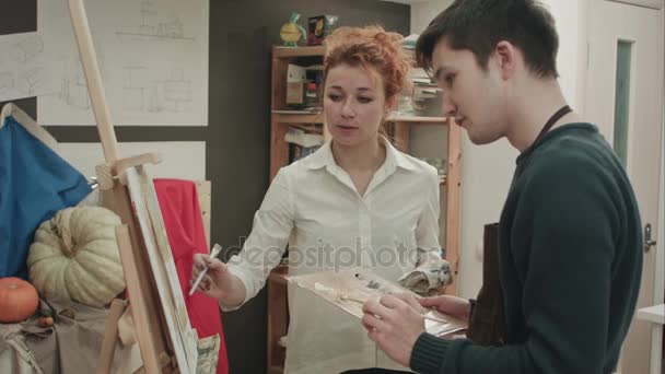 Insegnante di arte femminile che analizza la pittura con il suo studente maschio — Video Stock