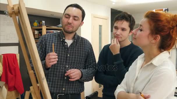 Étudiantes souriantes et enseignantes d'art analysant des œuvres d'art sur chevalet — Video