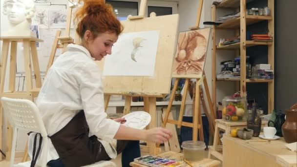 Joven artista femenina usando la pintura de paleta en su taller — Vídeo de stock