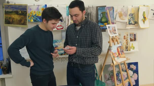 Dwóch młodych mężczyzn za pomocą smartfona w sztuce Klasa — Wideo stockowe