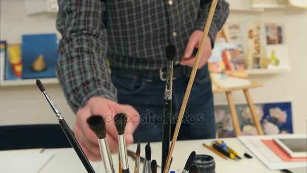 Hombre artista seleccionando pinceles de diferentes tamaños — Vídeos de Stock