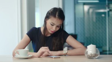 Telefonunu bir kafede denetlerken kahve zevk çekici genç kadın
